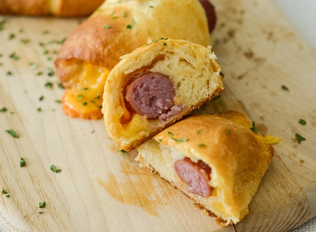 This image shows a cut open air fryer pigs in a blanket with cheese.